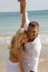 Young Couple Playing At Beach Stock Photo