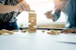 Hand Of Engineer Playing A Blocks Wood Tower Game (jenga) On Blu Stock Photo