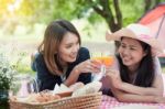 Two Asian Girlfriends Lying On The Lawn, Women In Park During Th Stock Photo