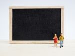 Miniature Children Standing In Front Of A Blackboard On Wooden B Stock Photo