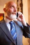 Middle-aged Businessman Listening On Smartphone At Home Stock Photo