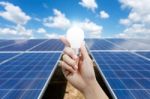 Solar Energy Panels And Light Bulb In Hand Stock Photo