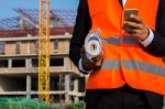 Young Engineer In Orange Shirt Stands Holding A Blueprint And Ta Stock Photo