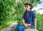 Young Man In A Cowboy Hat And Sunglasses Is Drinking Beer Stock Photo