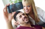 Beautiful Young Couple Using Mobile Phone At Home Stock Photo