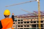 Young Engineer In Orange Shirt Stands Pointing At A Building Bei Stock Photo