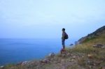 Backpack Man Standing On Rock Mountain And Looking To Ocean Use Stock Photo