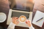 Hand On Cup Of Coffee At Work Table Stock Photo