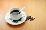 Cup Of Coffee With Beans On Wooden Table Stock Photo