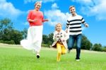 Happy Family Running In Park Stock Photo