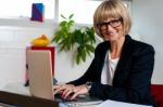 Smiling Female Manager Typing Report On Laptop Stock Photo