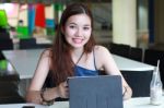 Portrait Of Thai Adult Beautiful Girl Using Her Tablet And Smile In University Stock Photo