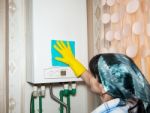 Woman Cleaning A Boiler With A Rag Stock Photo