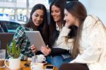 Three Young Woman Using Digital Tablet At Cafe Shop Stock Photo