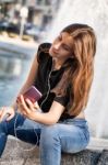 Young Woman Sitting  And Listening To Her  Music Stock Photo