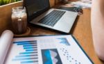 Coffee Cup  On A Table With Laptob And Graph Finance Diagram In Stock Photo