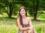 Young Beautiful Smiling Girl Sitting On The Grass Stock Photo