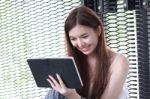 Portrait Of Thai Adult Beautiful Girl Using Her Tablet And Smile In University Stock Photo