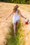 Happy Young Blonde Girl In White Dress With Straw Hat Running Th Stock Photo