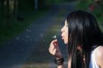 Woman Blowing A Dandelion Stock Photo