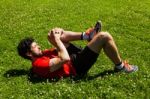 Urban Athlete Doing Stretching Exercises On The Grass Stock Photo