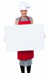 Smiling Female Chef Holding An Ad Board Stock Photo