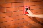 Hand Of Woman Is Pulling Fire Alarm On The Brick Wall Stock Photo