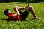 Urban Athlete Doing Stretching Exercises On The Grass Stock Photo