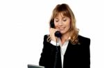 Smiling Female Executive Attending Phone Call Stock Photo