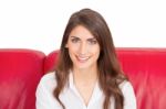 Smiling Young Woman With Brown Hair Sitting On Sofa Stock Photo