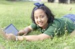 Girl Playing Computer Tablet On Green Field Stock Photo