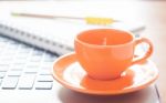 Laptop With Coffee Cup And Notepad On Desk Stock Photo