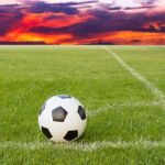 Soccer Ball On Soccer Field Against Sunset Sky Stock Photo