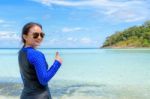 Happy Asian Woman Turning To Smile With Thumb Up At The Beach Stock Photo