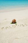 Maldives Written In A Sandy Tropical Beach And Coconut Fruit Stock Photo