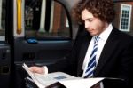 Businessman Reading Magazine Inside Taxi Stock Photo