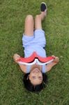 Asian Little Girl Reading Book In The Park Stock Photo