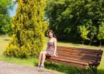 Young Woman Sitting On A Park Bench Stock Photo