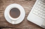 Laptop And A Cup Of Coffee On Old Wooden Boards. Computer Technology Concept Stock Photo