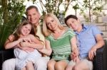 Happy Family Sitting In Patio And Looking At You Stock Photo