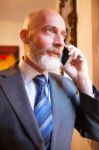 Middle-aged Businessman Listening On Smartphone At Home Stock Photo