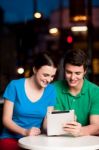 Couple Using Digital Tablet In Cafe Stock Photo