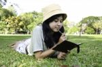 Woman Laying On Grass And Thinking In Park Stock Photo