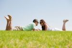 Couple Laying On Grass Lawn Stock Photo