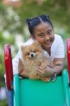 Girl And Pomeranian Dog In Field Stock Photo