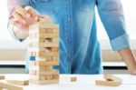 Hand Of Engineer Playing A Blocks Wood Tower Game (jenga) On Blu Stock Photo