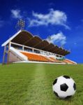 Soccer Football On Green Field With Stadium Background Stock Photo