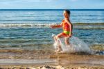 Happy Little Girl Making Splashes On The Beach Stock Photo