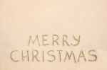 Merry Christmas Inscription On Wet Yellow Beach Sand Stock Photo