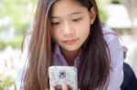 Portrait Of Thai High School Student Uniform Teen Beautiful Girl Using Her Phone And Smile Stock Photo